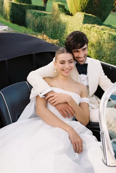 Bride and groom smiling joyfully together in a vintage car at Villa Arvedi gardens.
