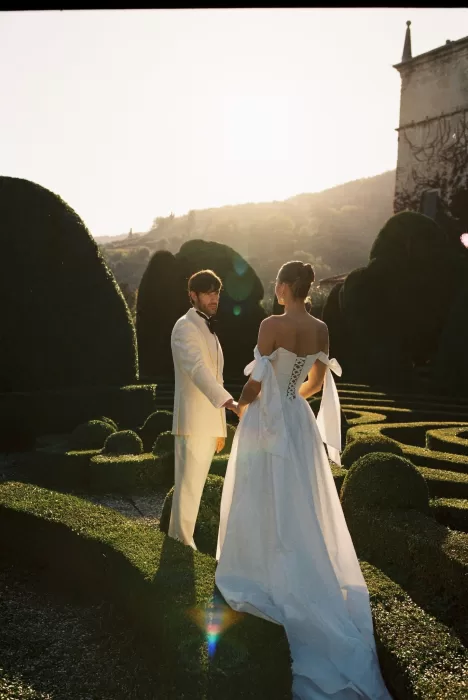 Couple framed by sunset light among Villa Arvedi’s sculpted garden hedges.