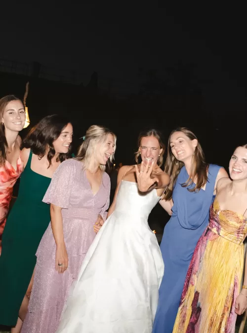 The bride laughing and showing off her ring surrounded by friends during a lively evening celebration at Villa San Vigilio.