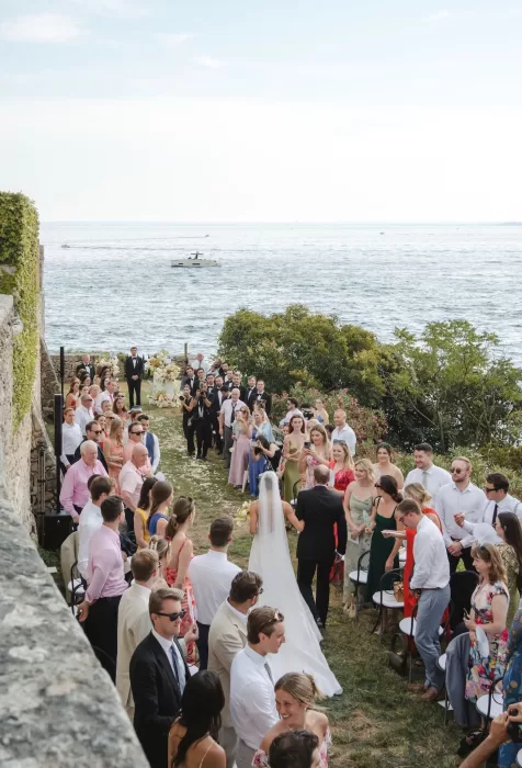 The bride walks down the aisle toward her guests with Lake Garda in the background at Villa San Vigilio.