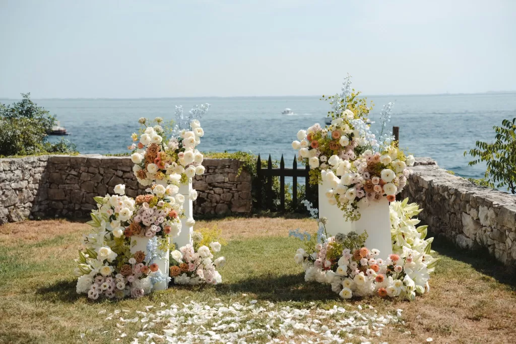 Lush floral ceremony setup overlooking Lake Garda at Villa San Vigilio, with pastel blooms and a stone wall backdrop.