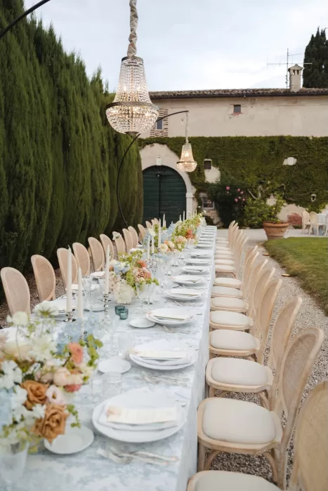 Elegant outdoor reception setup with a long candlelit table and crystal chandeliers at Villa San Vigilio.