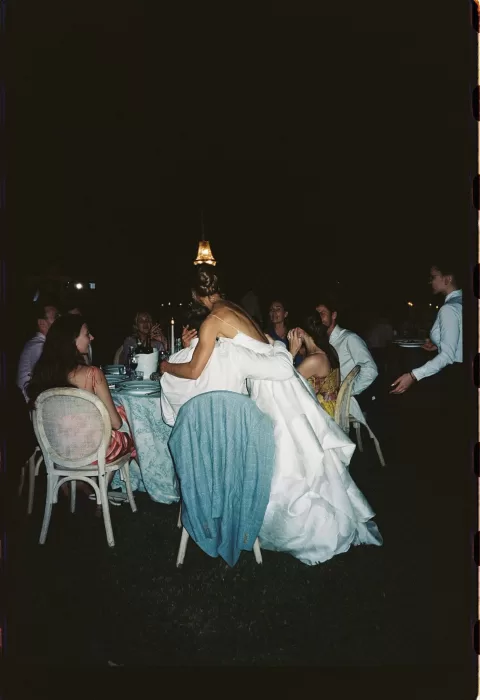 Intimate nighttime reception moment as the bride embraces a guest at a candlelit dinner at Villa San Vigilio.