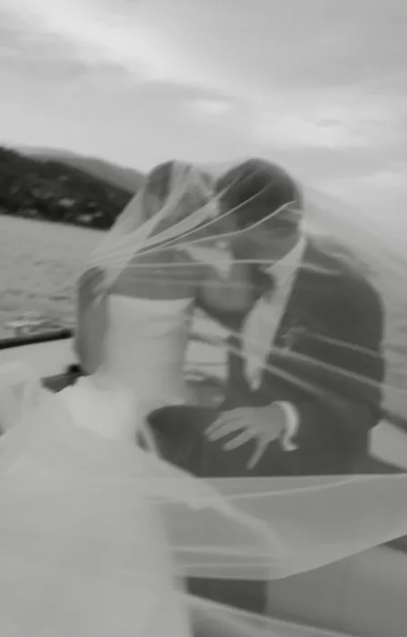 Artistic black and white portrait of the bride and groom kissing under the veil on a boat at Villa San Vigilio.