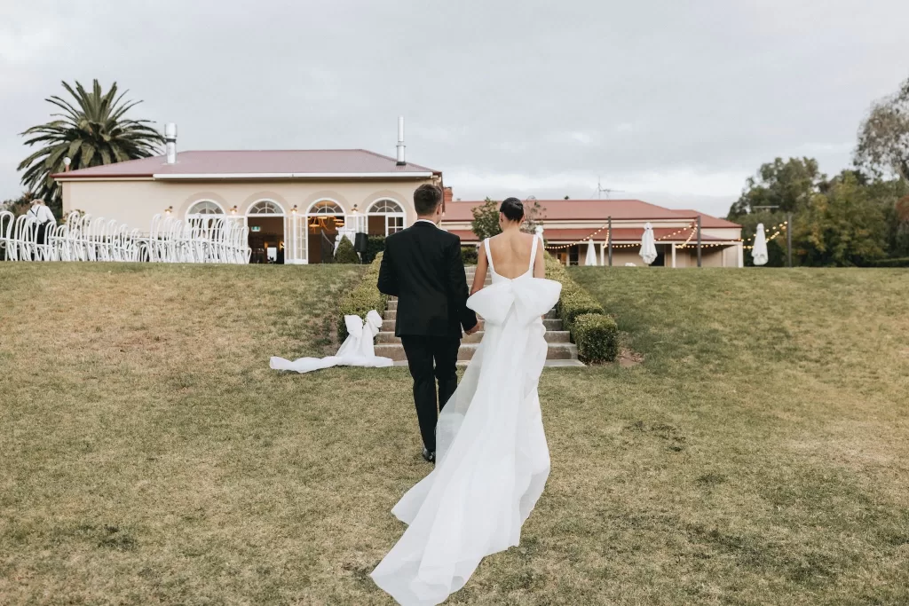 Newlyweds walking hand in hand towards the reception lawn at Le Mas Barossa.