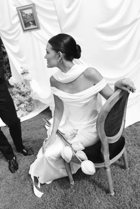 Black and white photo of the bride in an off-shoulder gown holding lotus flowers at Wallalong House.