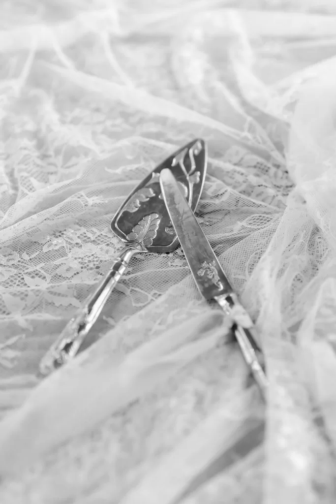 Elegant silver cake knife and server resting on lace fabric at Wallalong House.