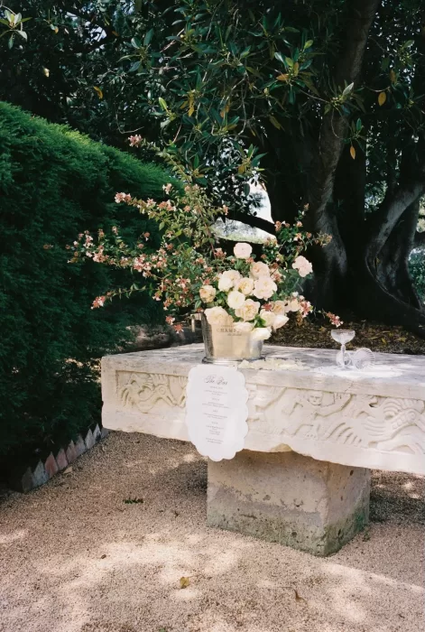 Romantic wedding bar setup with pastel roses in a silver vase on a carved stone table at Wallalong House.