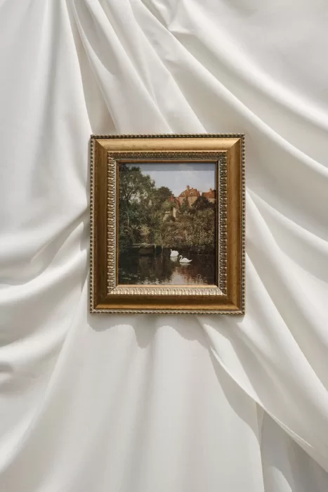 Framed vintage painting of swans displayed on a white draped backdrop at Wallalong House.