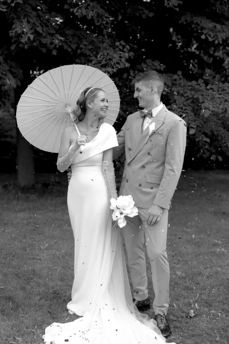 Bride and groom smiling under a white parasol during their Winery Hans Igler wedding.