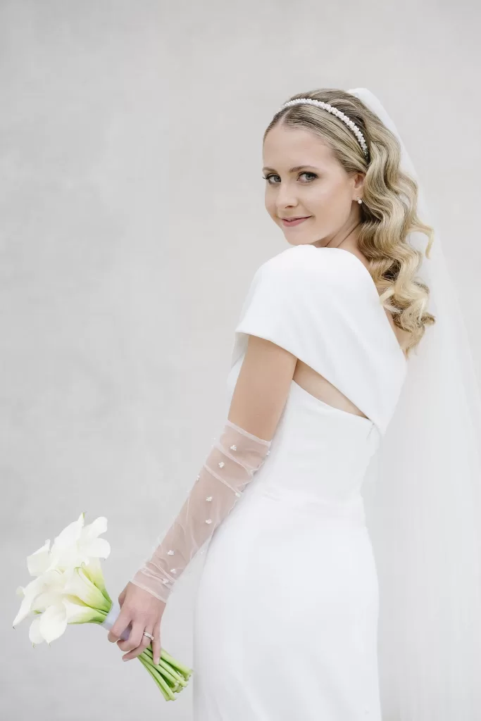 Elegant bride holding calla lilies and smiling over her shoulder at Winery Hans Igler.