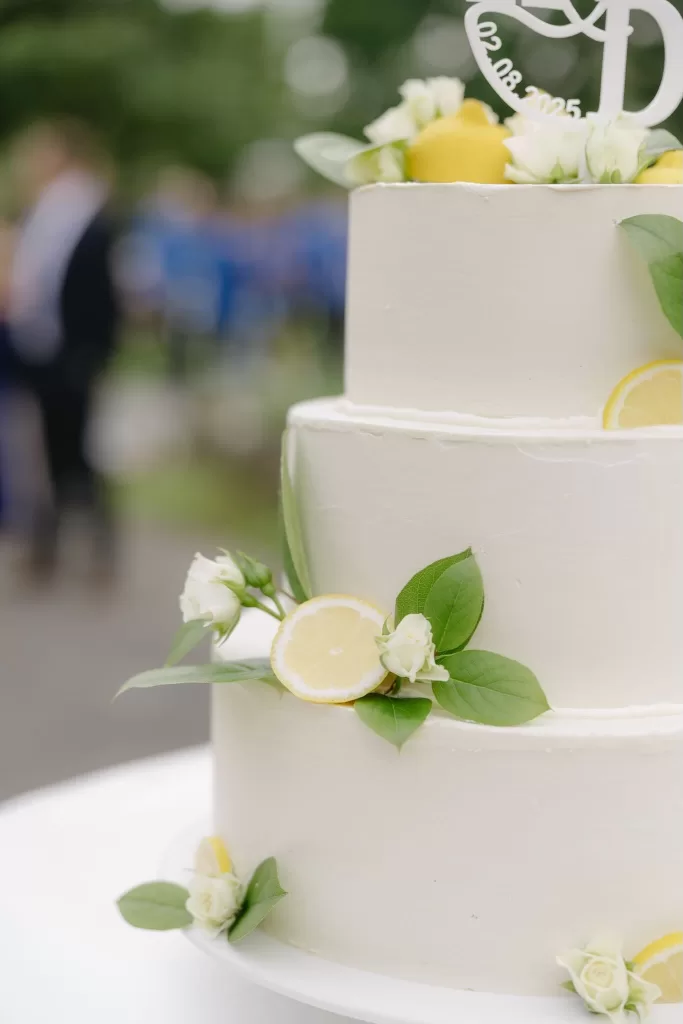 Three-tier white wedding cake decorated with fresh lemons and white flowers at Winery Hans Igler.