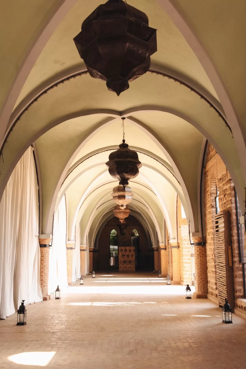 Elegant vaulted hallway with Moroccan lanterns and soft natural light at Beldi Country Club.