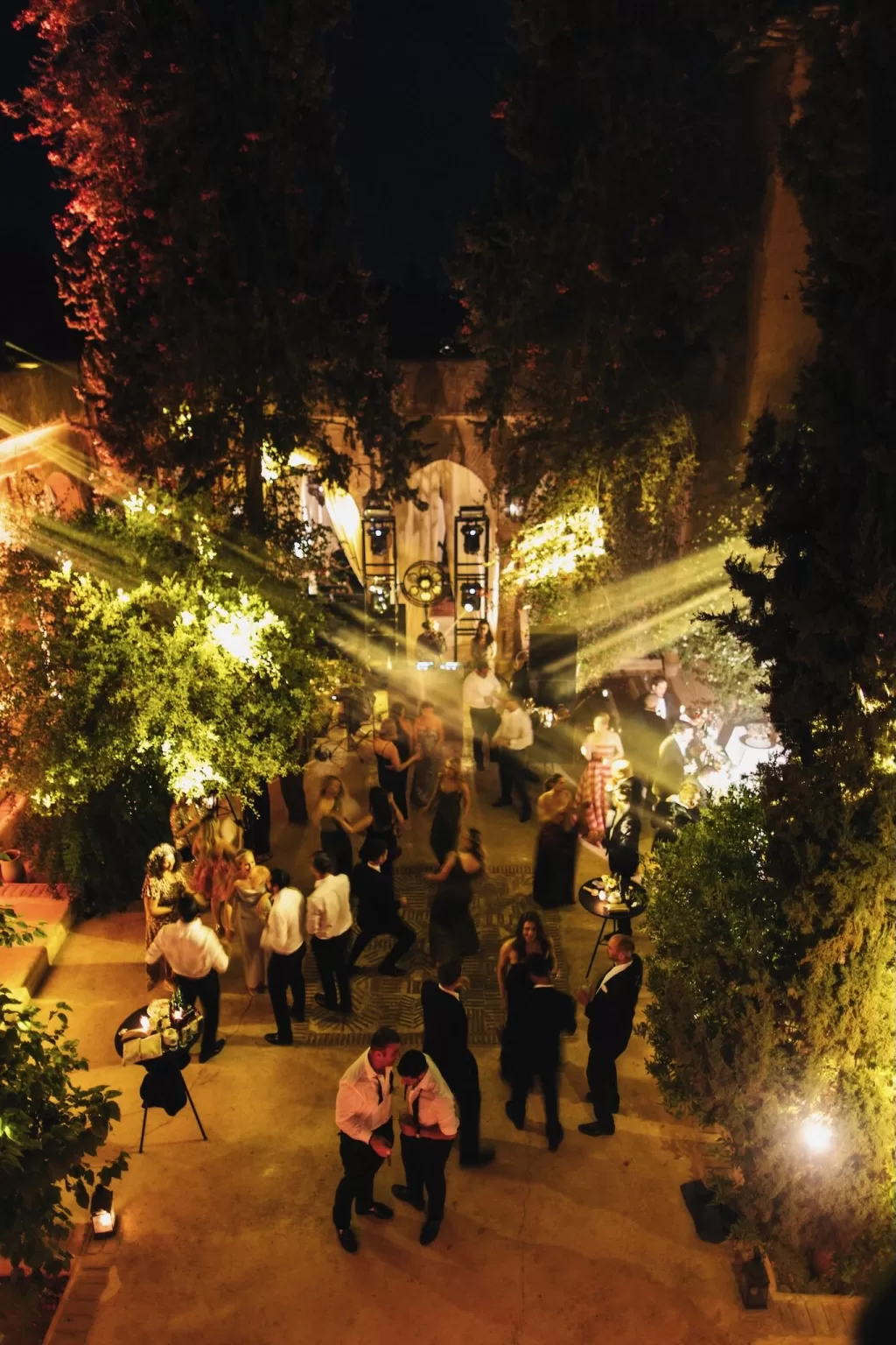 Guests dancing under dramatic lights in the courtyard at Beldi Country Club during a lively wedding celebration.