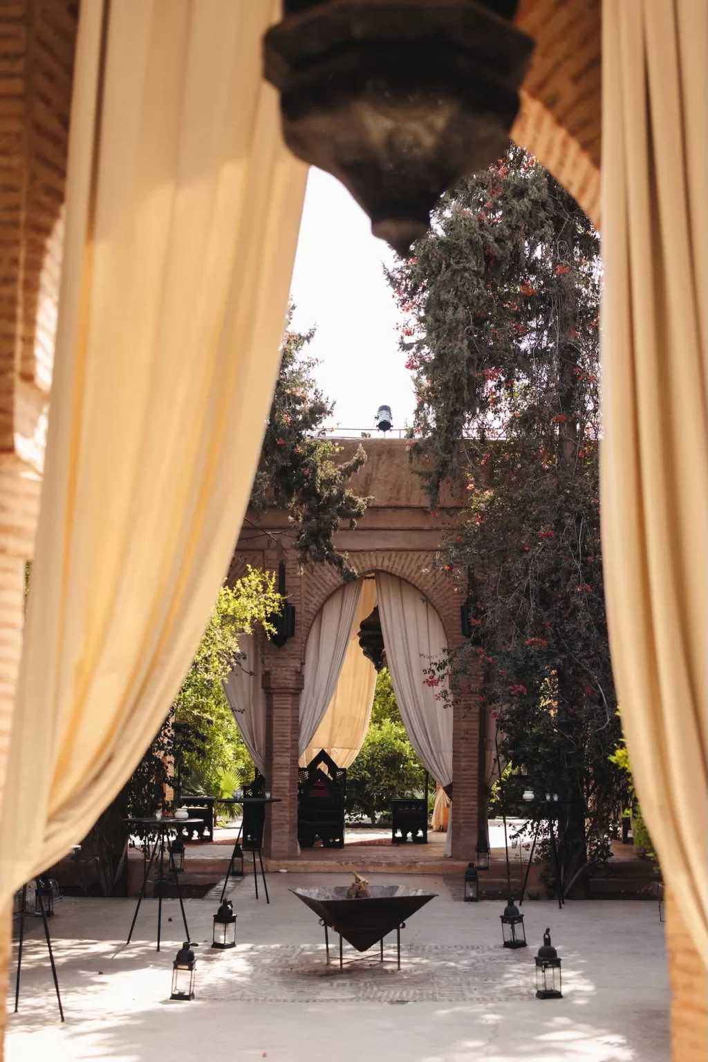 Elegant Moroccan arches with draped curtains and lanterns at Beldi Country Club courtyard.