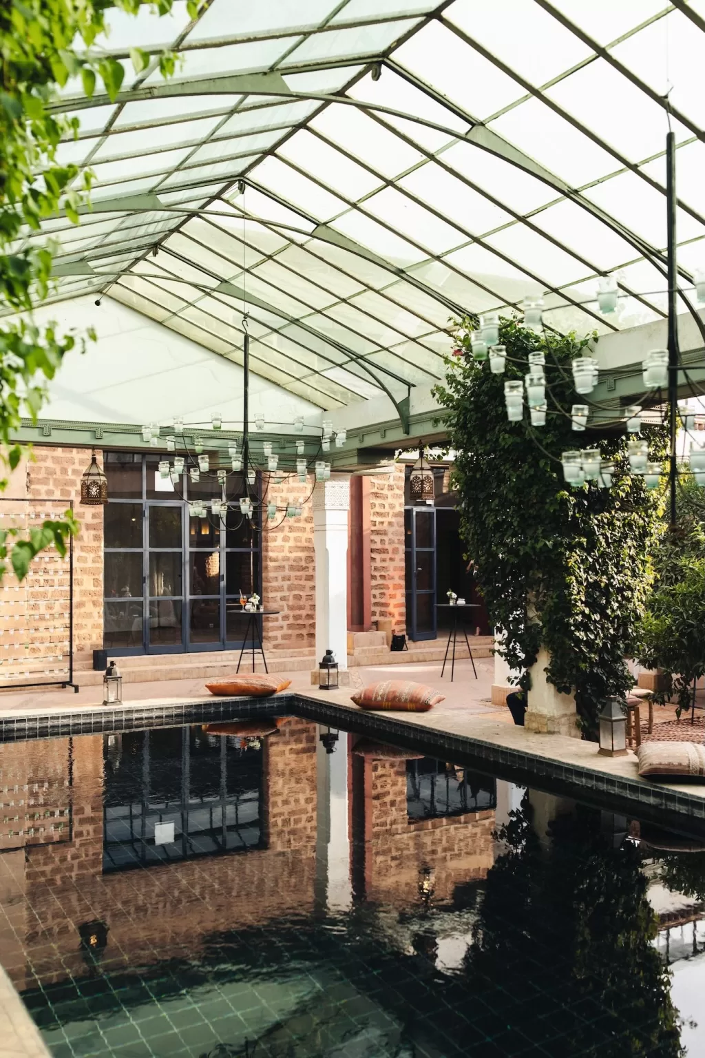 Covered poolside area at Beldi Country Club decorated with lanterns, chandeliers, and Moroccan pillows.