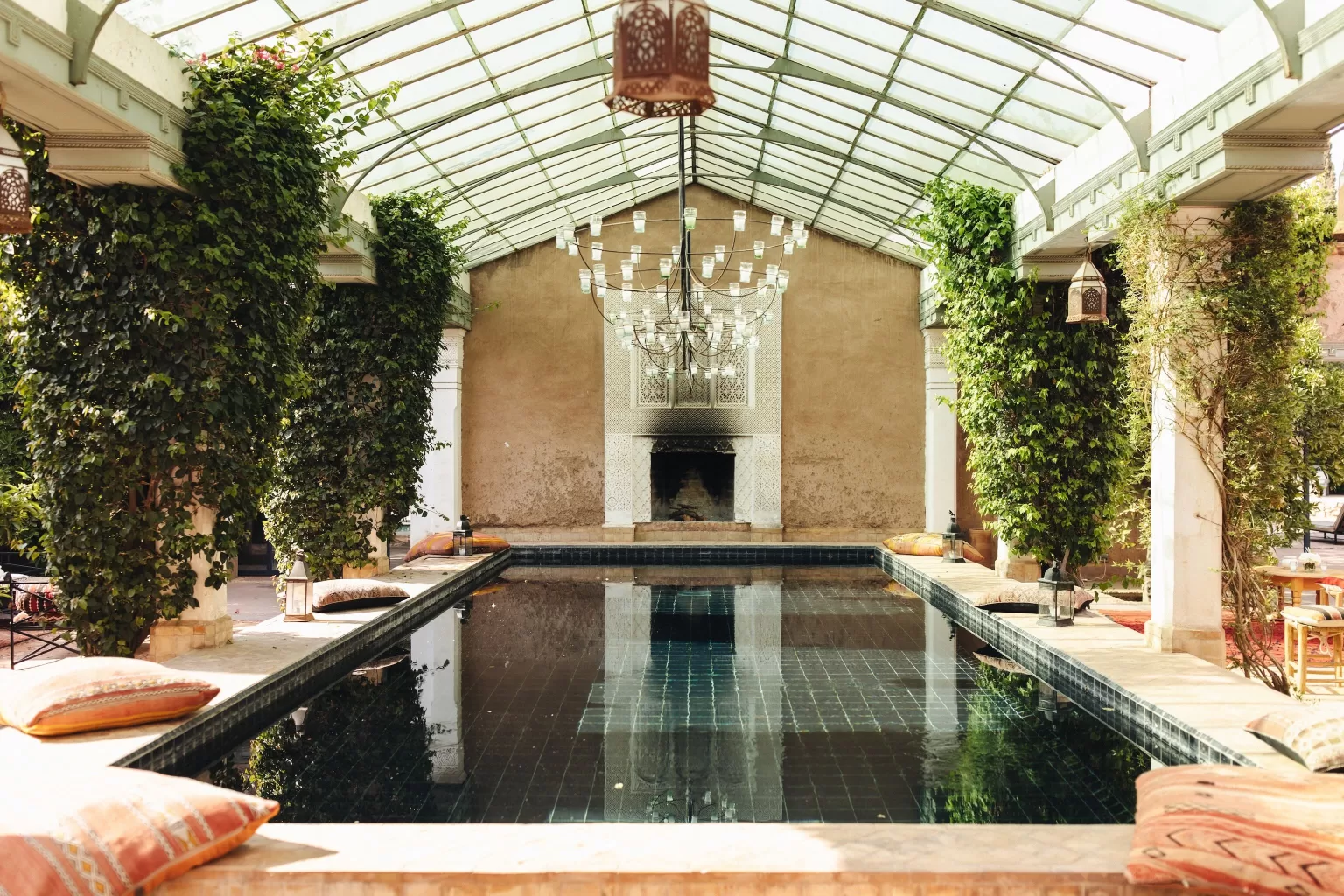 Still water pool reflecting chandeliers and ivy-covered pillars at Beldi Country Club.