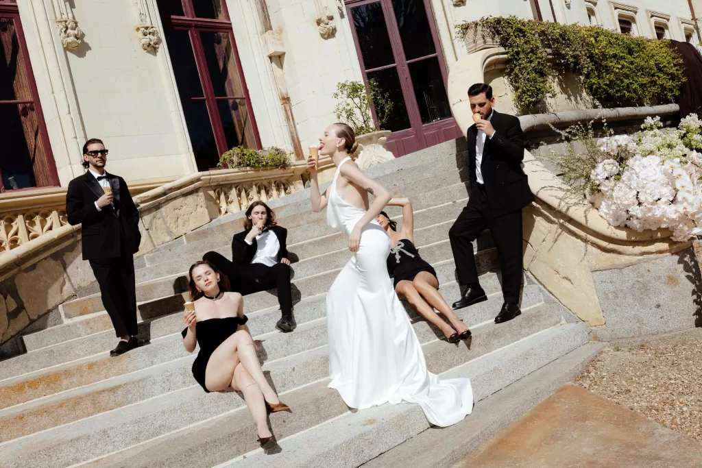 Bridal party relaxing and enjoying ice cream on the grand stone steps of Chateau Challain.
