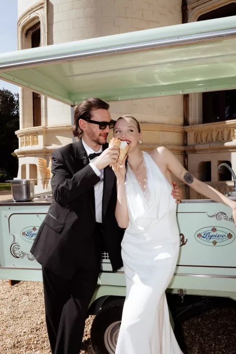 Bride and groom laughing together while sharing ice cream cones outside Chateau Challain.