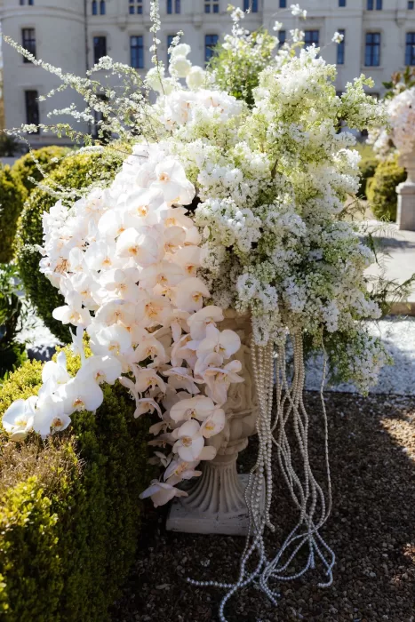 Luxurious floral arrangement of orchids and white blooms with pearls at Chateau Challain wedding.
