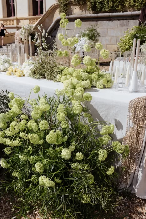 Wedding reception table decorated with lush green florals, candles, and pearls at Chateau Challain.