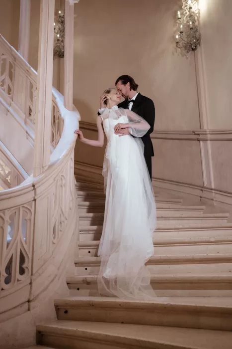 Bride and groom embracing on the sweeping stone staircase inside Chateau Challain.