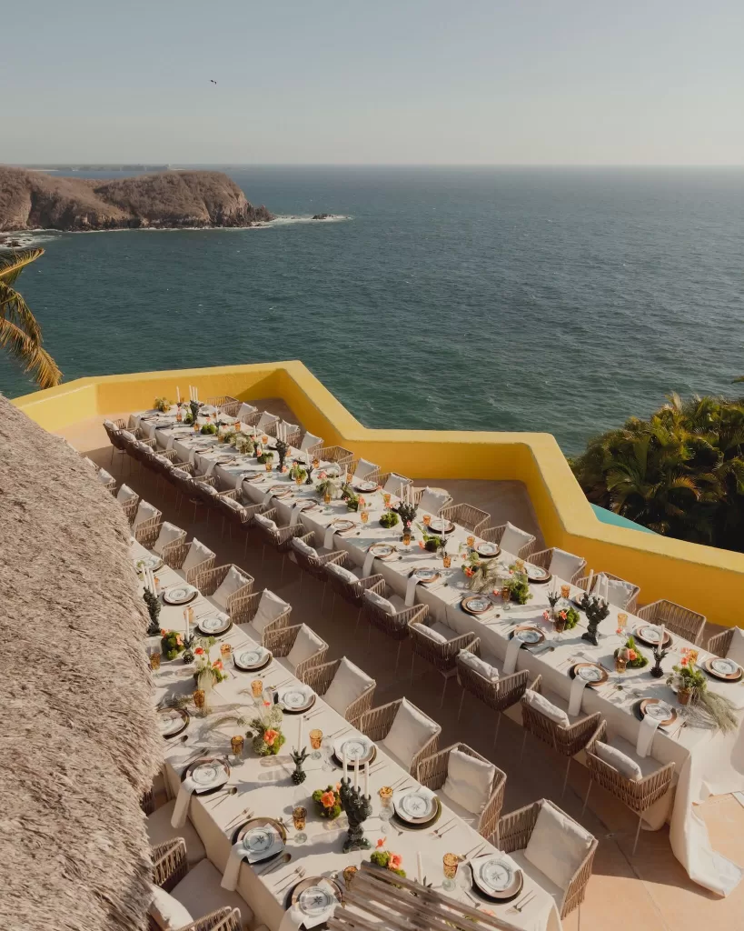 Long reception tables overlooking dramatic cliffs and the sparkling ocean.