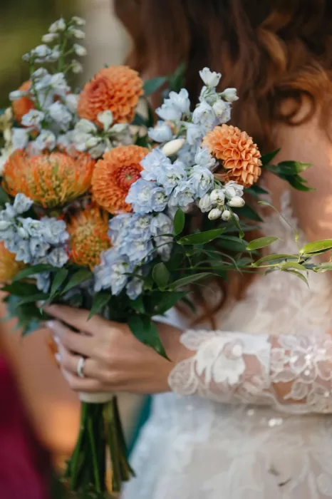 Bride holding a wild bouquet of blue delphinium and orange dahlias at Finca Son Collell