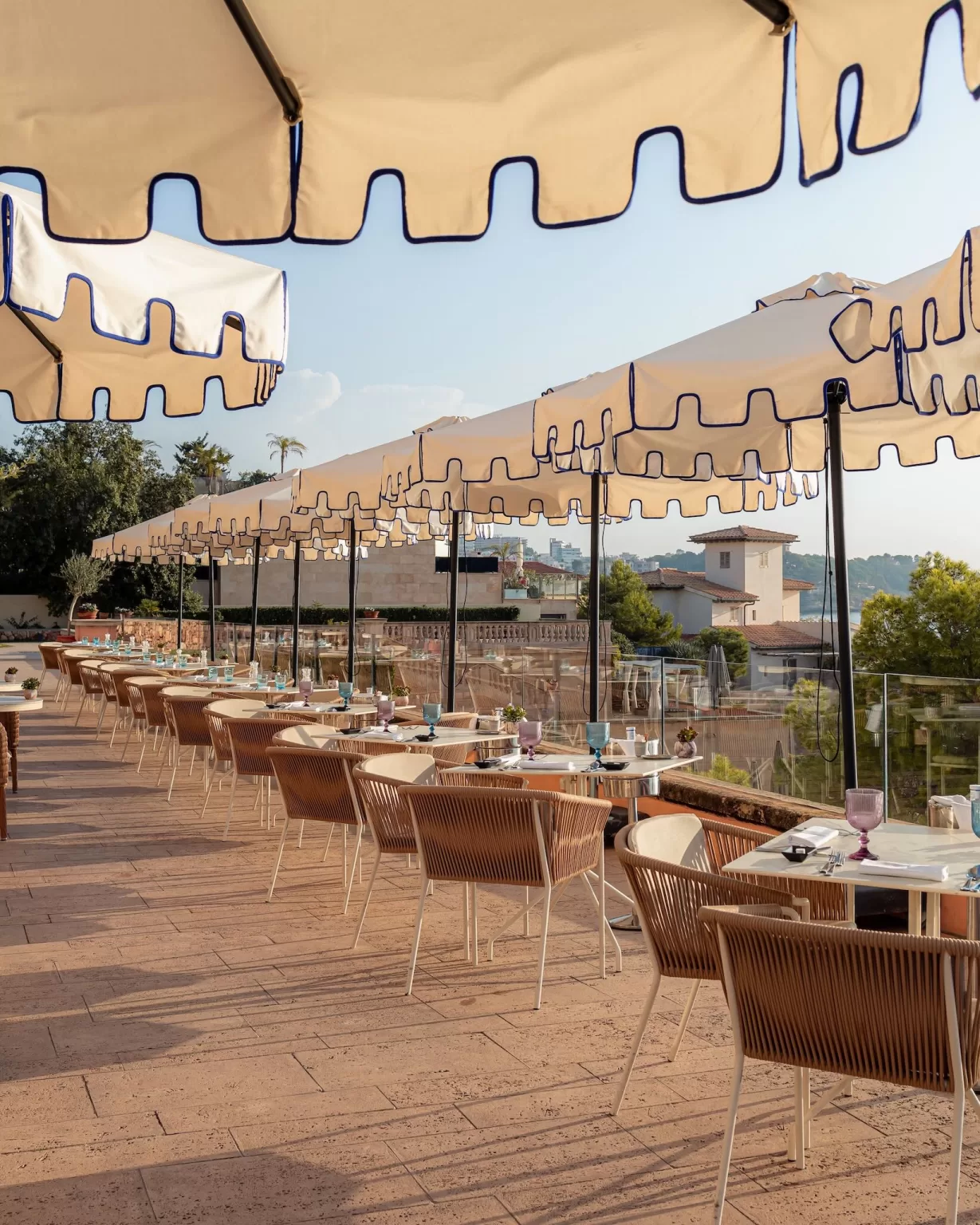 Outdoor dining terrace at Hospes Maricel & Spa with striped parasols and views across Palma Bay.
