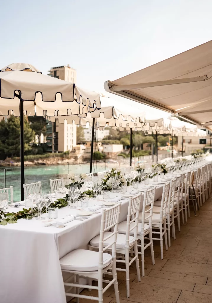 Long banquet table with white flowers and greenery on the seaside terrace of Hospes Maricel & Spa.