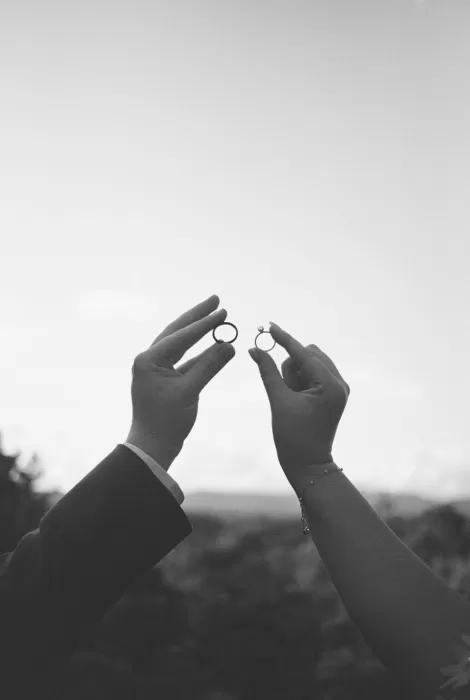 Bride and groom hold their wedding rings up against the sky in a romantic detail shot at House Boheme.