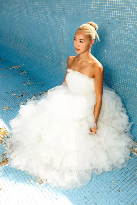 Bride in a layered tulle gown seated in an empty turquoise pool at La Finka 4.1.