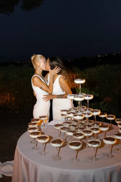 Brides sharing a kiss beside a champagne tower under the night sky at La Finka 4.1.