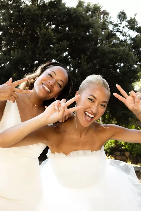 Brides smiling and flashing peace signs in a joyful outdoor moment at La Finka 4.1.