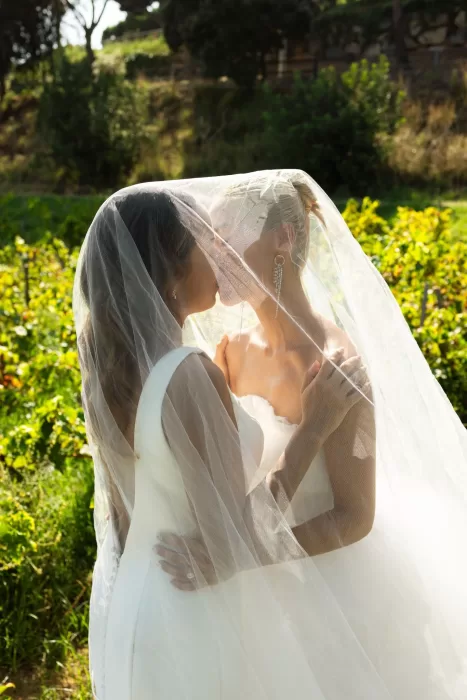 Brides sharing a romantic kiss under a veil in the gardens of La Finka 4.1.