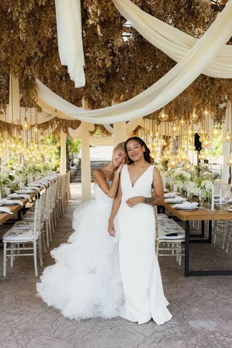 Brides embracing under a canopy of lights and golden foliage at La Finka 4.1 reception.