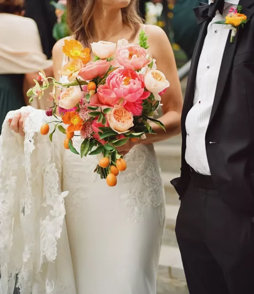 Vibrant bouquet of pink and orange flowers held by the bride at Laguna Gloria.