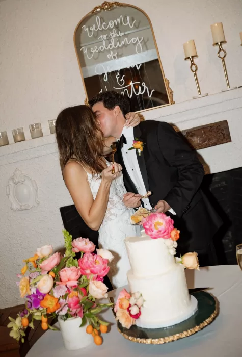 Bride and groom kissing while cutting their wedding cake at Laguna Gloria.
