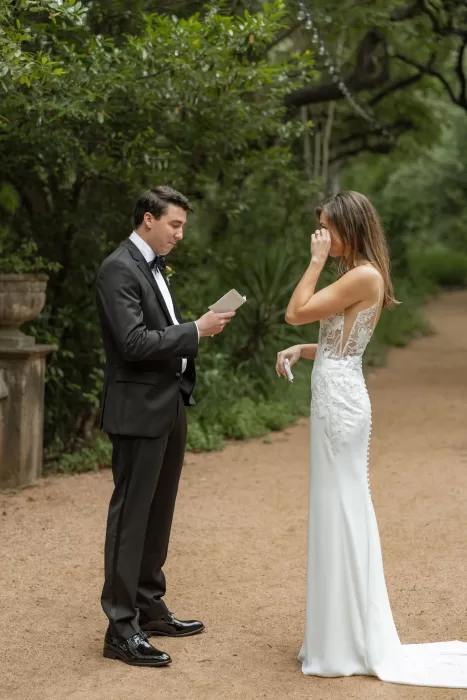 Groom reading heartfelt vows as bride wipes away tears at Laguna Gloria.