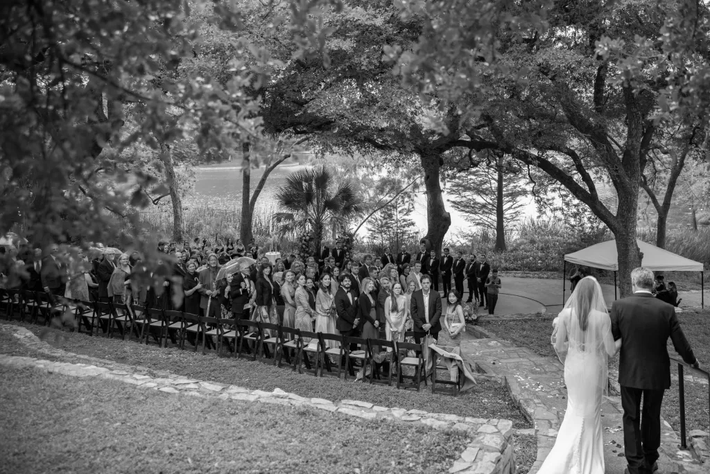 Guests turning to watch the bride walk down the outdoor aisle at Laguna Gloria.