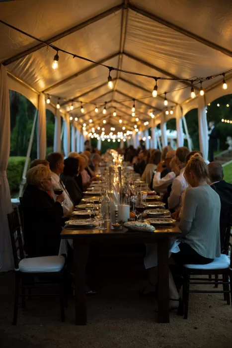 Guests seated at a long candlelit table under a tent with string lights at Laguna Gloria.
