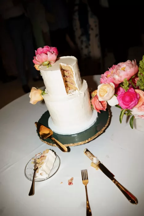 Partially sliced white wedding cake with floral decorations at Laguna Gloria.