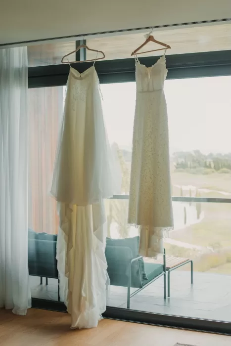 Two wedding dresses hanging by the window at Mas de Les Voltes.