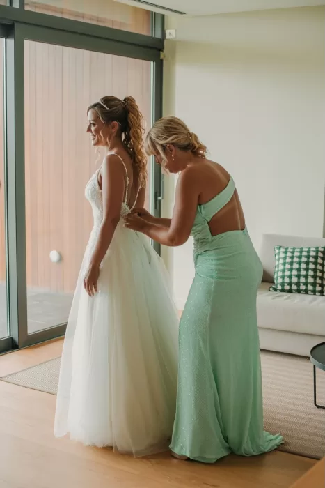 Bride getting ready with bridesmaid adjusting dress at Mas de Les Voltes.