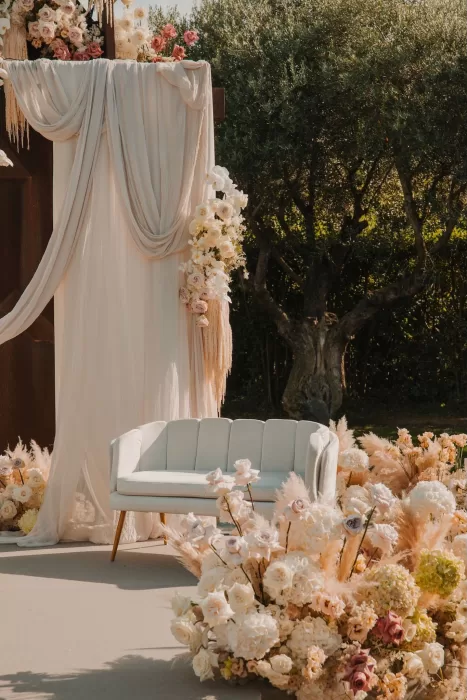 Elegant floral ceremony lounge with draped fabric and pastel flowers at Mas de Les Voltes.