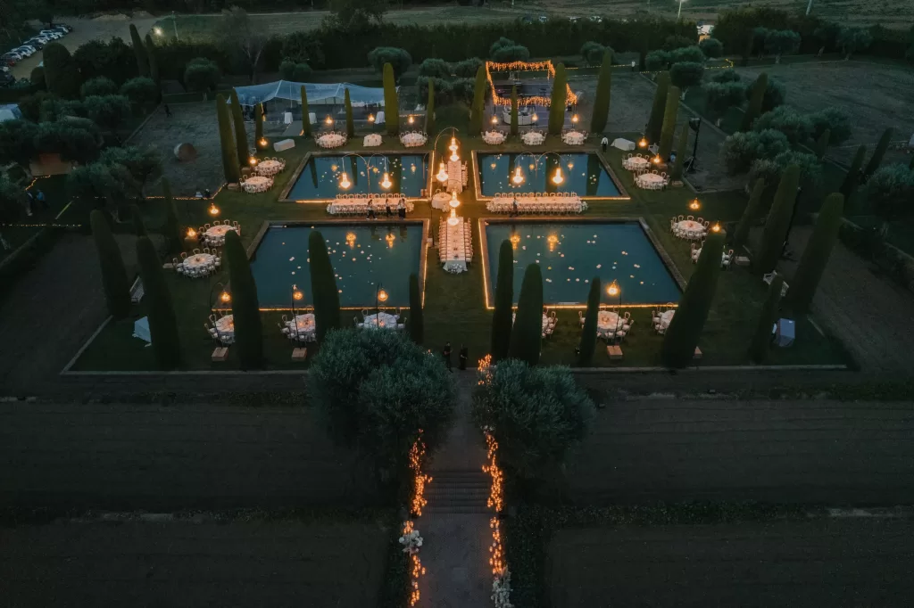 Night aerial view of Mas de Les Voltes wedding dinner with glowing chandeliers and pools.