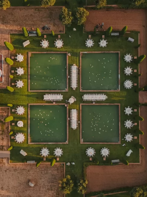 Overhead view of poolside wedding dinner setup with round tables at Mas de Les Voltes.