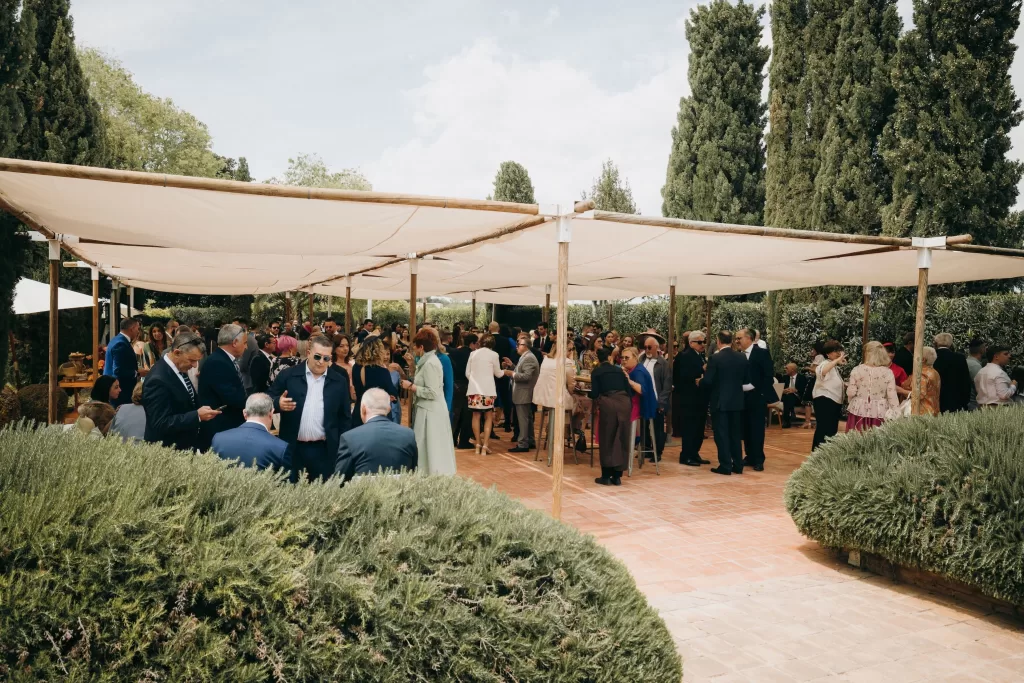 Guests mingling under shaded canopy during outdoor cocktail reception at Masia Aldamar.
