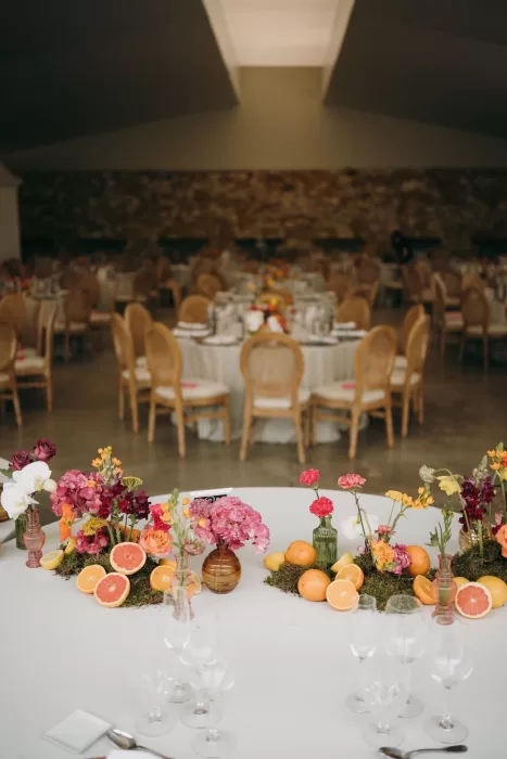 Wide view of reception setup at Masia Aldamar with citrus and floral arrangements across tables.