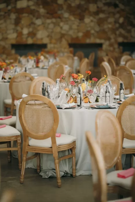 Elegant round tables with neutral linens and citrus-inspired floral decor at Masia Aldamar reception.